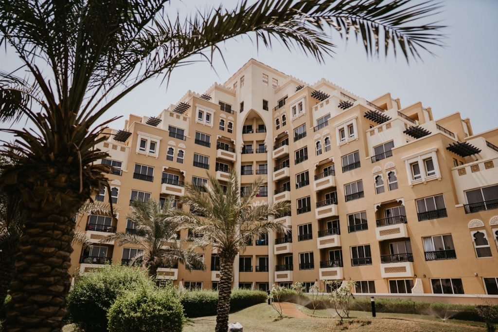 Low angle view of a modern hotel building in Dubai surrounded by palm trees.